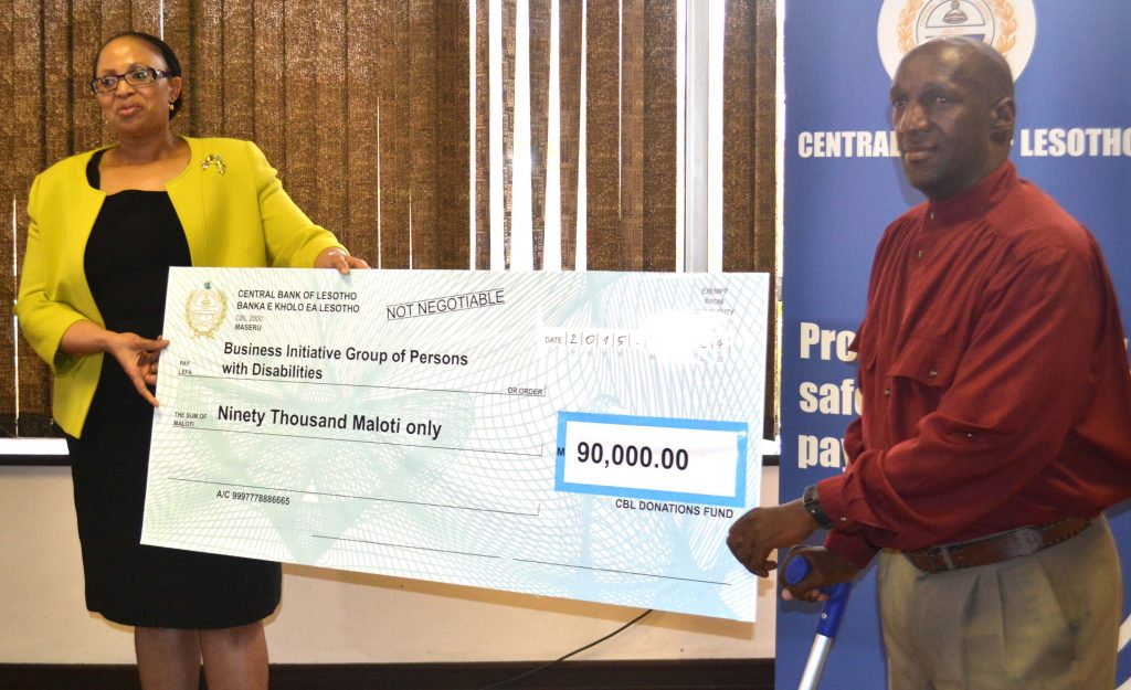 Business Initiative group of Persons with Disability Founder Seabata Lengosane accepts a cheque from governor Matlanyane 