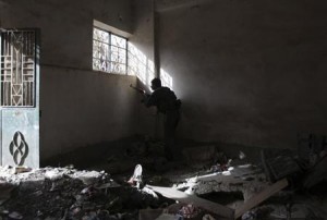 A Free Syrian Army fighter takes up position as he sneaks a look out of a window in Deir al-Zor