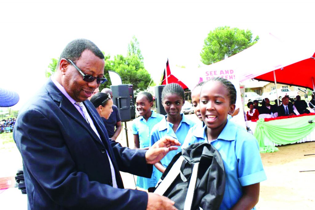 Deputy Minster of Education and Training Thabang Kholumo gives students bags